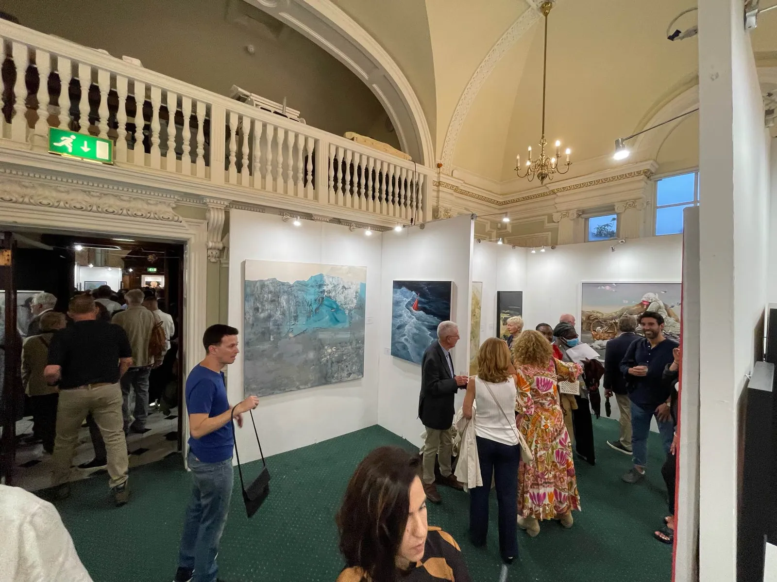 Visitors and artists gathered under the vaulted ceiling of Chelsea Old Town Hall during the London Art Biennale 2023 opening