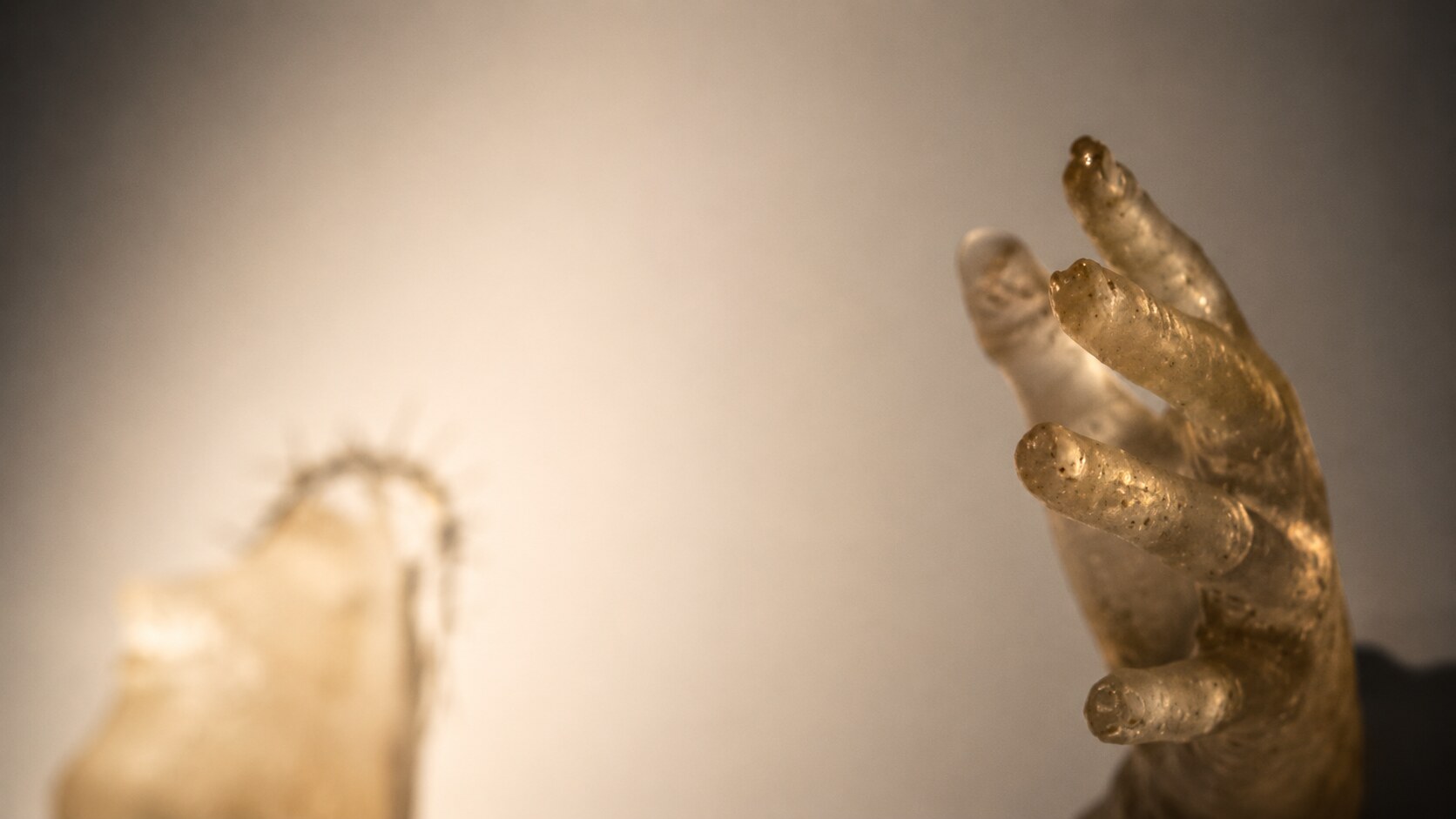 Close-up of a hand cast in translucent resin with amber-golden tones, detail from the Metha-Lan installation — Adrian Dică, AnnArt Gallery, 2014
